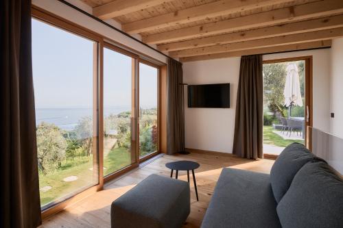 a living room with a couch and large windows at Colago Private Villas Lake Garda in Toscolano Maderno