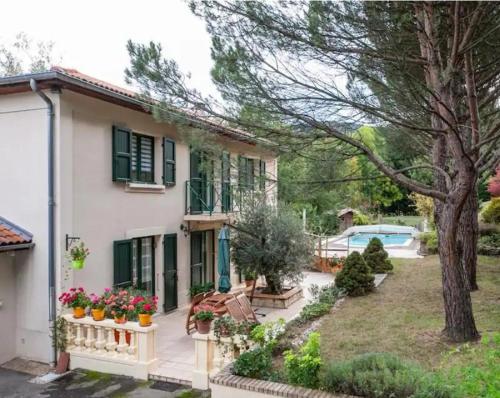 a white house with green shutters and a yard at Maison familiale campagne piscine forêt in Saint-Chamond