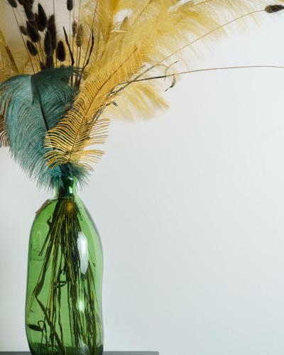 a green glass vase with feathers in it at Curtigghiu Mondello in Mondello