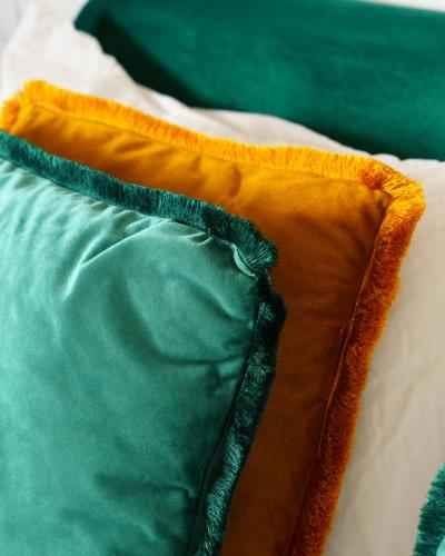 an orange and green pillow on a bed at Curtigghiu Mondello in Mondello