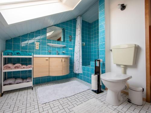 a bathroom with a toilet and a blue tiled wall at Haus Pia in Pfalzgrafenweiler