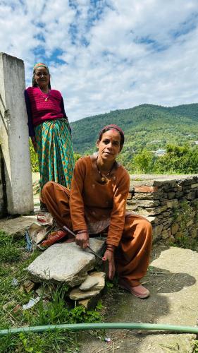 a man sitting on a rock with a woman behind him at Saanidhya Homestay in Mukteswar