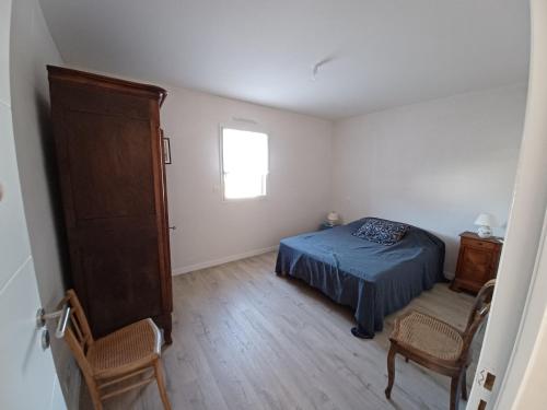 a bedroom with a bed and two chairs and a window at Saint-Cast-Le-Guildo in Saint-Cast-le-Guildo