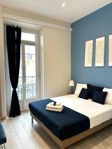 une chambre avec un lit aux murs bleus et une fenêtre dans l'établissement Harmonie Nature au cœur de Nice, à Nice