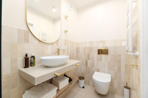 a bathroom with a sink and a toilet and a mirror at Hetman Main Square Apartments in Krakow