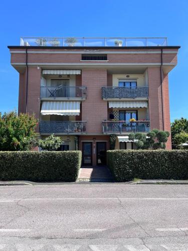 a red brick building with a balcony and bushes at La finestra su Assisi in Bastia Umbra