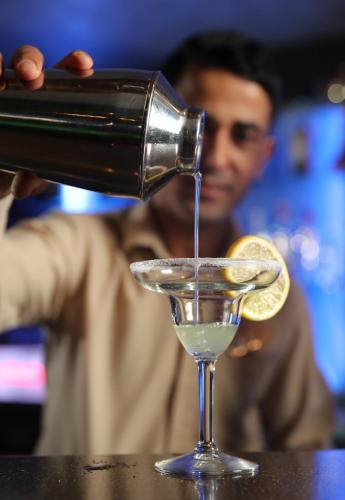 a man pouring a drink into a martini glass at Hotel Muscat Holiday in Muscat