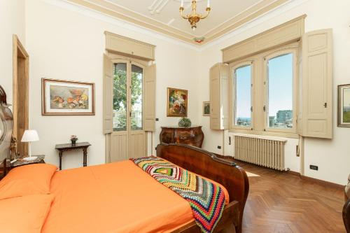 sypialnia z pomarańczowym łóżkiem i oknami w obiekcie Villa Amerigo Vespucci Sea View w Genui