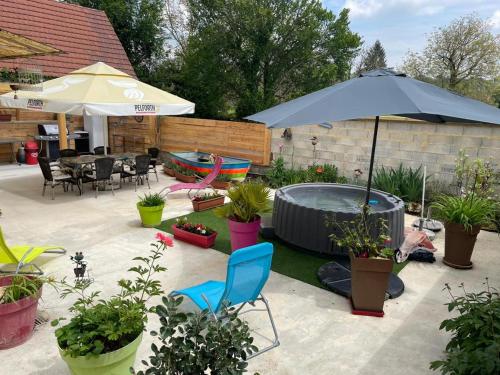 a patio with a hot tub and an umbrella at La petite barque in Saint-Julien-de-Lampon