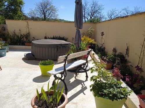 a patio with a bench and an umbrella and potted plants at La petite barque in Saint-Julien-de-Lampon