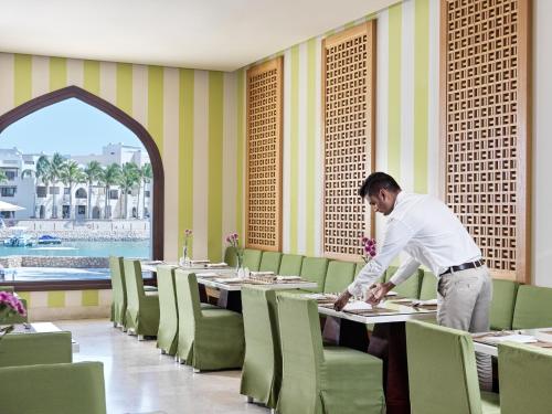 a man standing at a table in a dining room at Juweira Boutique Hotel Adult only in Salalah