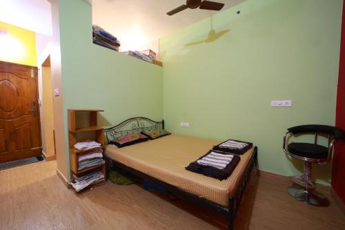 a small bedroom with a bed and a chair at Chithralaya Guest House in Yercaud
