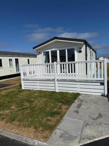 a white mobile home with a white fence at 36 Lighthouse View in Lossiemouth
