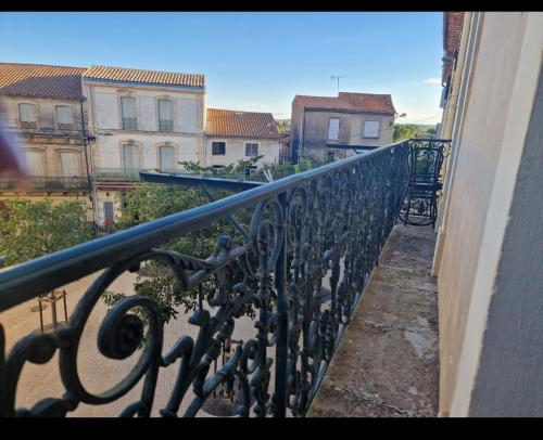 un balcon avec une balustrade en fer avec des bâtiments en arrière-plan dans l'établissement Le Petit Servian, à Servian