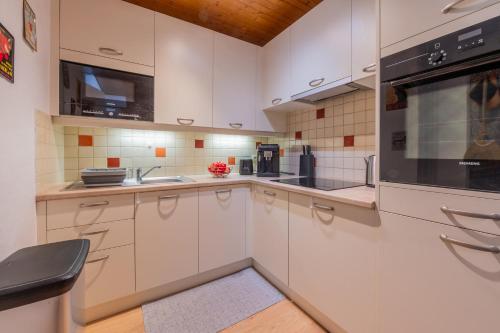 une cuisine avec des armoires blanches et des appareils noirs dans l'établissement Le Refuge Du Bouchet - Happy Rentals, à Chamonix-Mont-Blanc