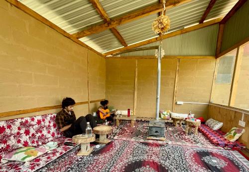 two people sitting on a couch playing a guitar at Sifar - Stay & Art Café, Shangarh in Shangarh