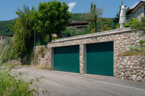 two green garage doors in a stone building at Appartamenti Alla Lanterna in Costermano sul Garda