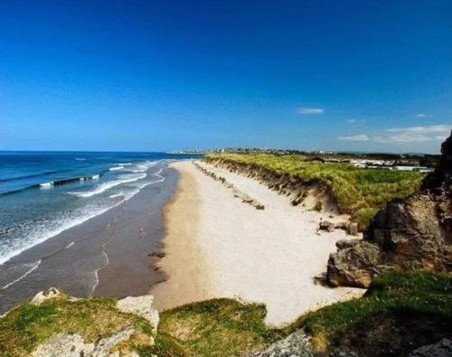 a beach with rocks and the ocean on a sunny day at 36 Lighthouse View in Lossiemouth