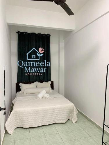 a bedroom with a bed with a sign on the wall at Qameela Mawar Homestay in Sandakan