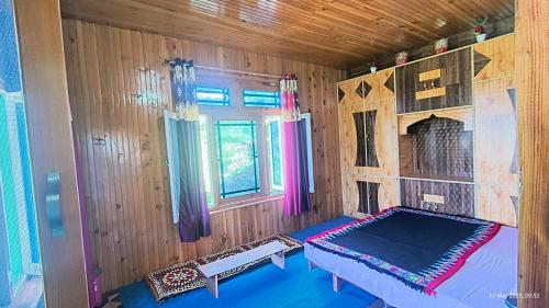 a room with a bed in a wooden room at Aurelia by Xtastays - Deohari, Sainj Valley, Kullu in Sainj