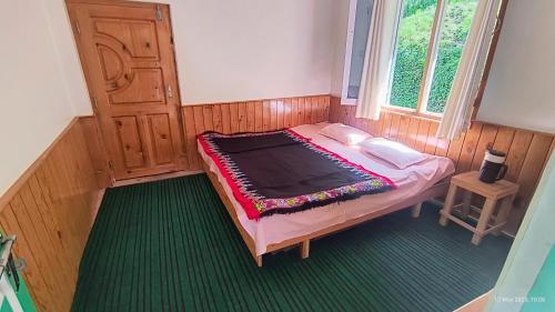 a small bedroom with a bed and a window at Aurelia by Xtastays - Deohari, Sainj Valley, Kullu in Sainj