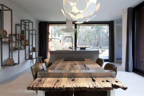 a dining room with a wooden table and a chandelier at Stalen Boshuis by Droomvilla in Oosterhout