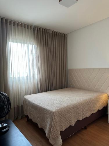 una camera da letto con un letto e una finestra con tende di Piscina,sauna ,ar condicionado a 30passos da Bacutia a Guarapari