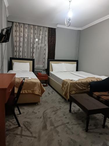 a bedroom with two beds and a table and a desk at Büyük Akçay hotel in Erzurum