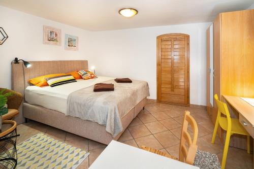 een slaapkamer met een bed, een tafel en een bureau bij Studio Apartment Tea in Baška