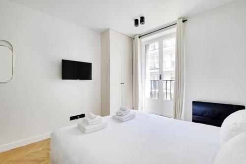 une chambre blanche avec un lit et une télévision dans l'établissement Pick A Flat's Apartment in Tour Eiffel - Rue du Champs de Mars, à Paris