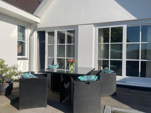 a patio table with chairs and windows at Aan de Wiericke in Driebruggen