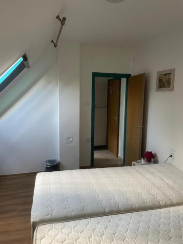 a bedroom with a white bed and a hallway at Turul Panzió&Pizzéria in Szólád