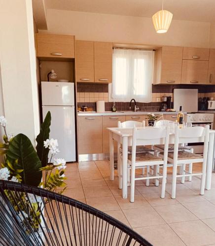 a kitchen with white tables and chairs and a white refrigerator at Rosa Viola in Corfu