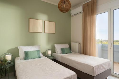 two beds in a room with a window at Pithos Apartment in Korakiaí