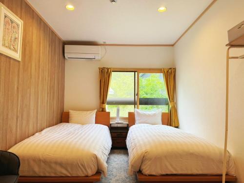 two beds in a room with a window at 軽井沢フォーシーズホテル in Karuizawa