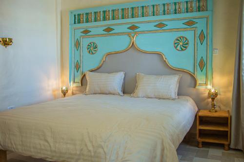 a bedroom with a large white bed with a blue headboard at Dar Shams Riad Medina de Sousse in Sousse