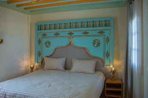 a bedroom with a large bed with a blue headboard at Dar Shams Riad Medina de Sousse in Sousse