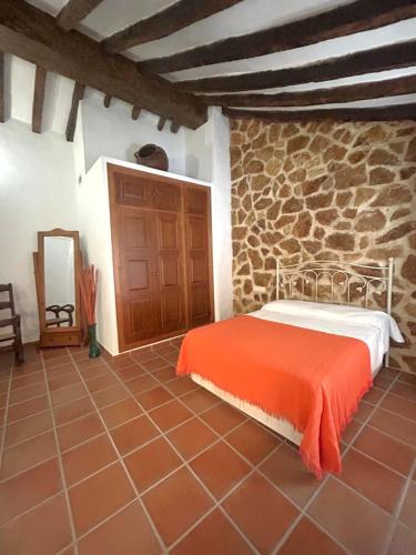 a bedroom with a bed and a stone wall at Casa Gómez in Gaucín