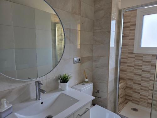 a bathroom with a sink and a mirror and a toilet at Oliva Home in Los Cristianos