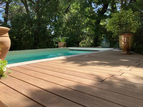 a pool with a wooden deck and some plants at La Balouvière Villa entre Cévennes et Provence in Laudun