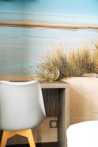 a white chair sitting next to a table with the ocean at Hôtel du Midi Plage in Palavas-les-Flots