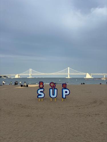 a sign on a beach with a bridge in the background at g HOUSE in Busan