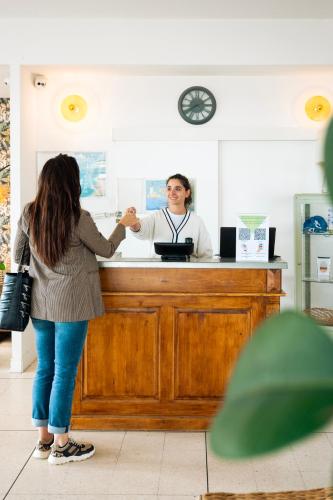 a woman standing at a counter with a man at Hôtel du Midi Plage in Palavas-les-Flots