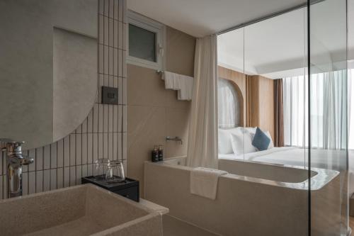 a bathroom with a tub and a bed and a mirror at Kin Hotel Thai Van Lung in Ho Chi Minh City