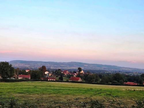 a green field with a town in the distance at Le confort sans chichis, un cocon pour 1 à 6 voyageurs in Lapeyrouse