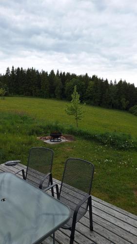 two chairs and a table on a deck with a field at Chata Luční in Klíny