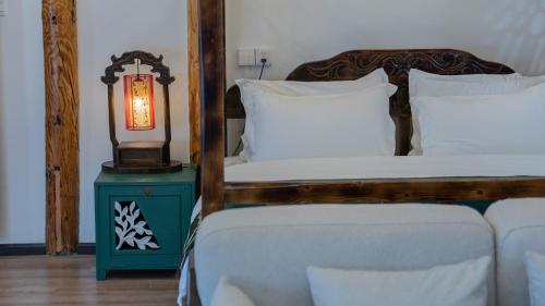 a bedroom with a bed and a lamp on a table at Yiyuan Snow Mountain View Historical Naxi House - Lijiang Old Town Mufu branch in Lijiang