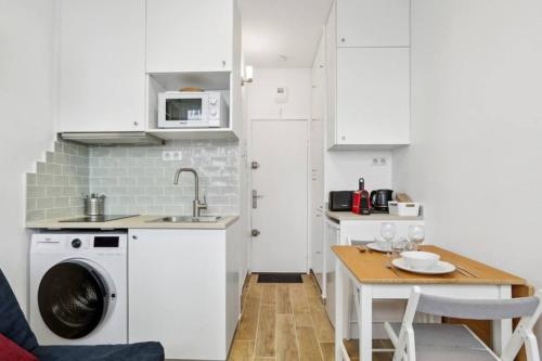 une petite cuisine avec une table et un lave-linge. dans l'établissement Studio bien équipé à proximité du Parc des Princes, à Paris