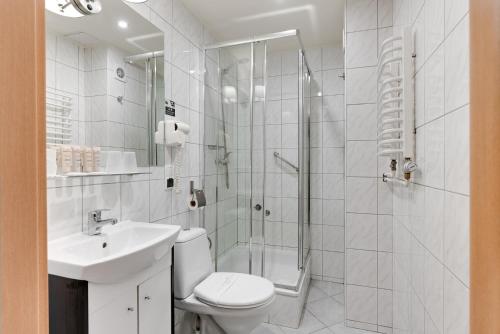 a white bathroom with a shower and a toilet and a sink at Hotel Diament Zabrze - Gliwice in Zabrze