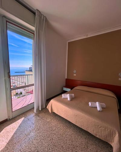 a bedroom with a bed and a large window at Hotel ROSE NUOVE in Rimini